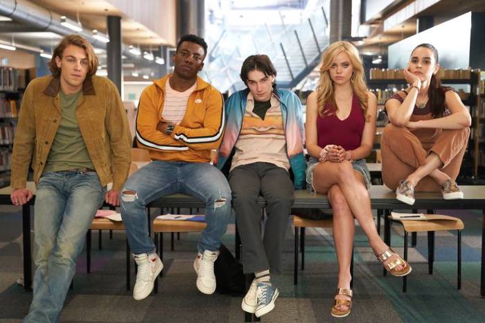 5 personnages principaux dans la série Qui ment?, assis sur des tables d'école, face caméra regard caméra. Young Adult spoil